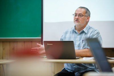 Man sitting at a desk talking with a laptop in front of him