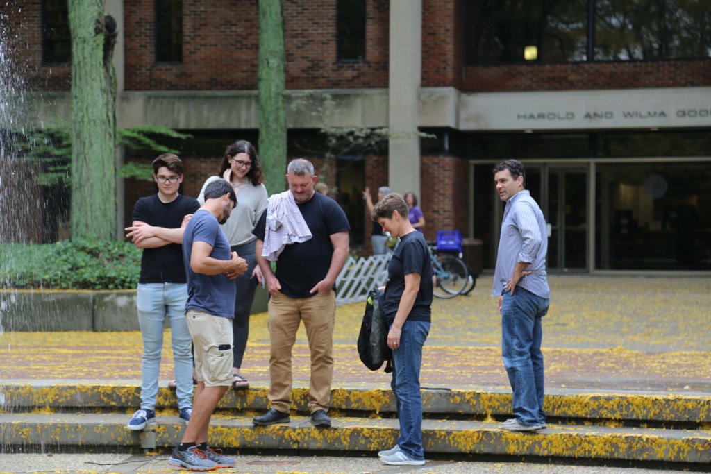 A group of people standing on concrete steps looking at the ground