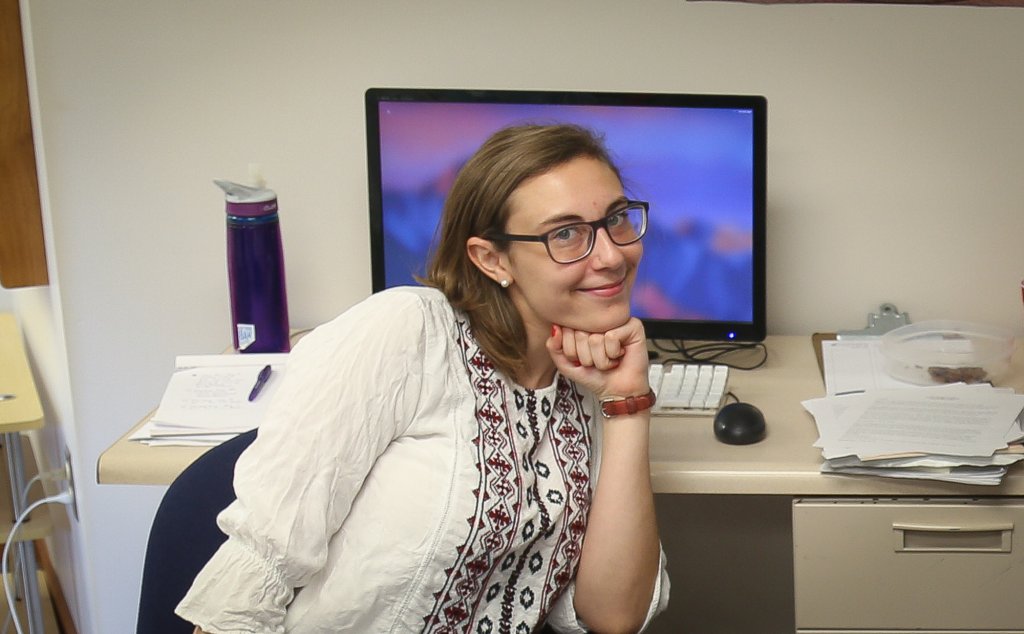 Woman posing in front of a desktop computer