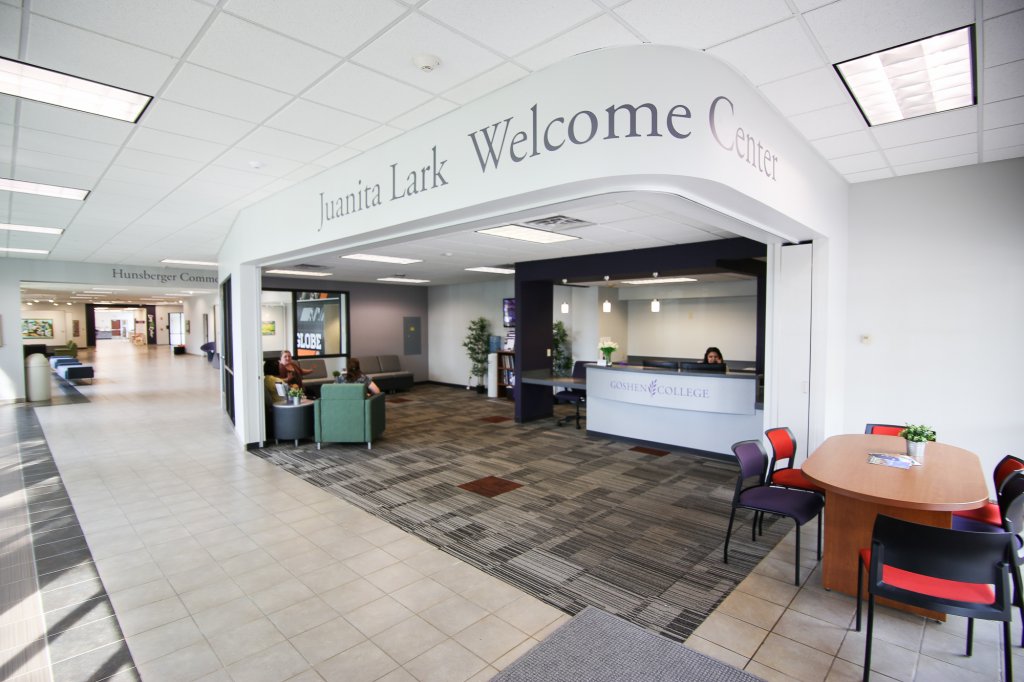 Welcome center with a woman at the front desk and chairs and a table off to the side