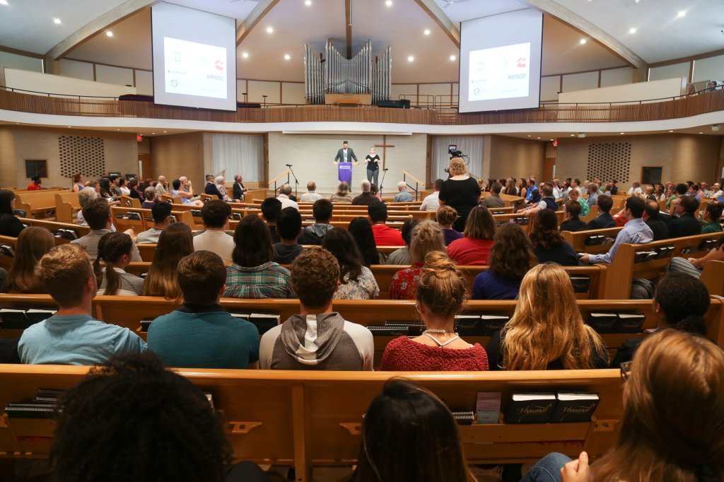 Man speaking at a podium at the front of a church full of people