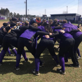 A group of athletes wearing purple and black in a huddle