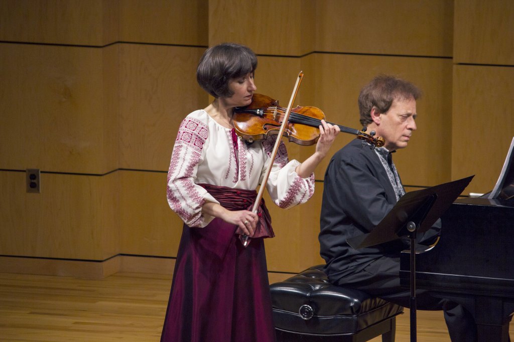 Woman playing a violin next to a man who is playing piano