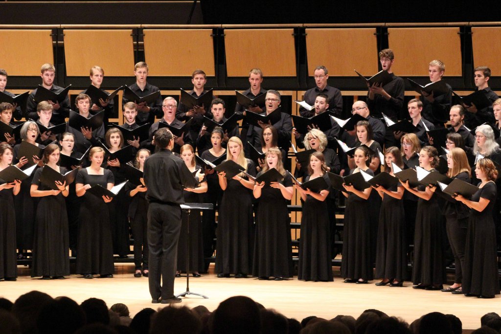 Group of people of all ages singing in a choir on stage