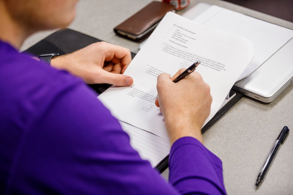 Person filling out a worksheet while sitting at a table