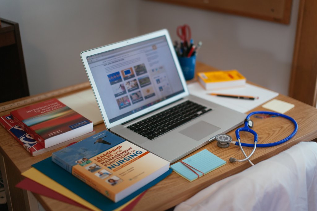 A laptop, stethoscope, and textbooks at a desk