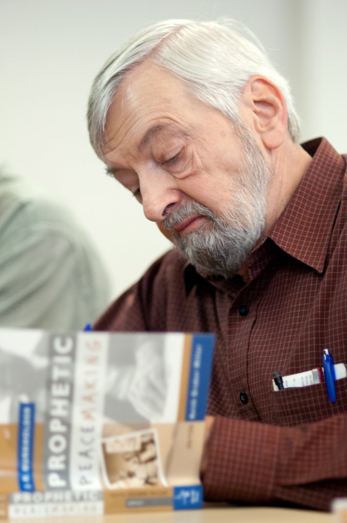 Man reading a book called 'Prophetic Peace Making'