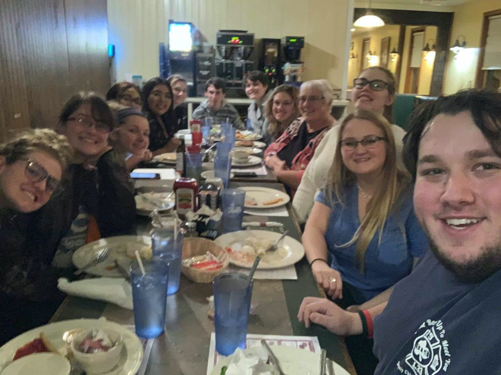 Group of people sitting at a table in a restaurant smiling at the camera