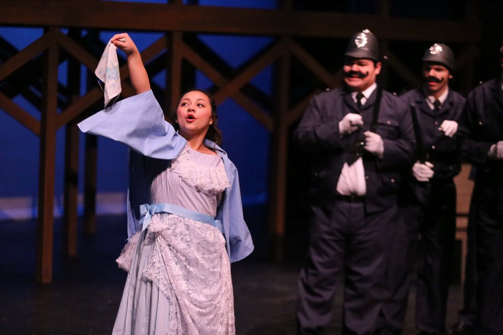 Woman standing on stage with police officers in the background