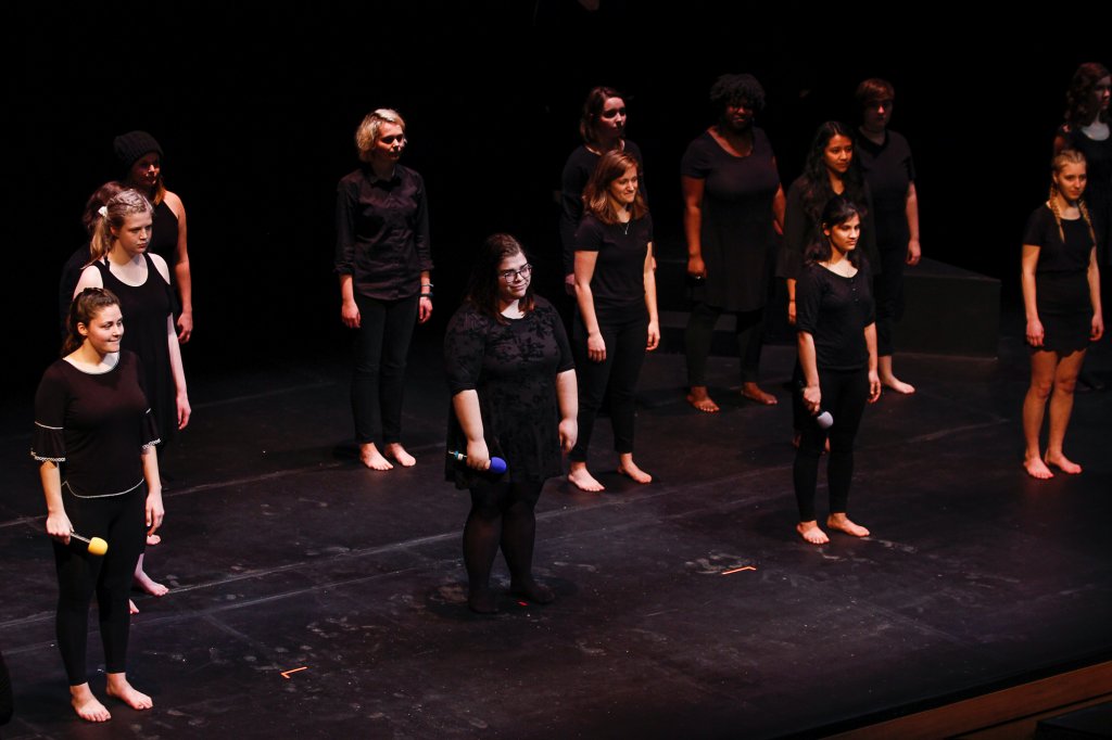 A group of women standing on a stage barefoot wearing black