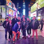 Group of people posing for a photo with lots of glowing advertisements and lights around them