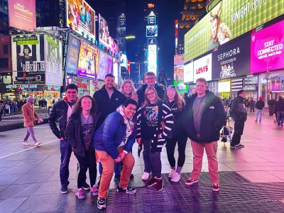 Group of people posing for a photo with lots of glowing advertisements and lights around them