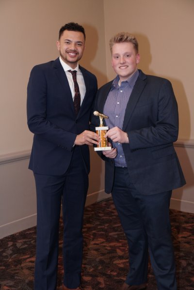 Two men posing for a photo while holding an award