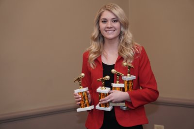 Woman holding four awards